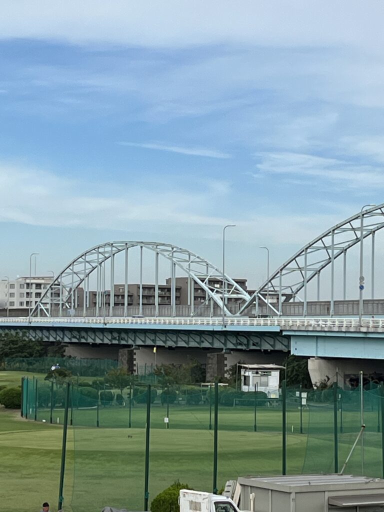 鉄橋の下に広がる緑のフィールド。都会の午後に残る静かな余白。