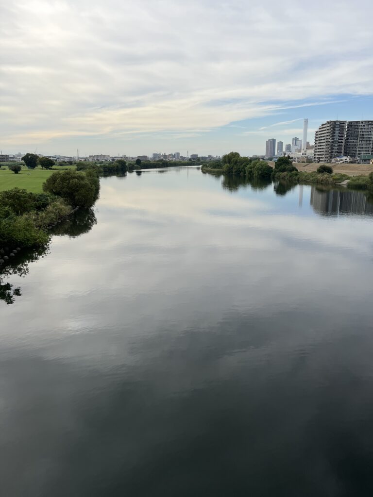 夕方の光を映す多摩川の水面。雲と空が溶け合うように流れていく。